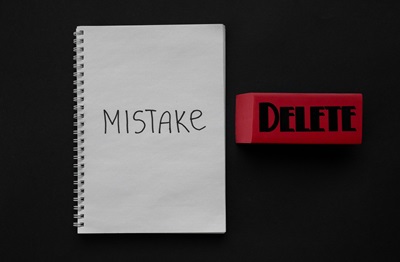An eraser with "Delete" written on it next to a notebook with "Mistake" written on it