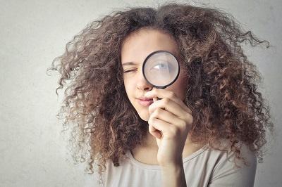 A woman holding a magnifying glass to her eye