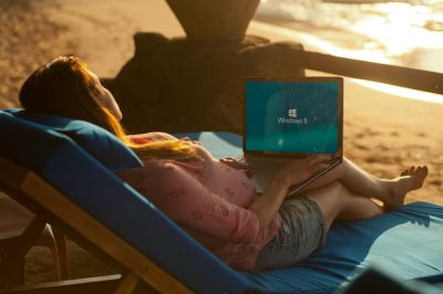 A woman using a laptop on a beach