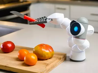 A robot holding a knife appearing to cut some fruit