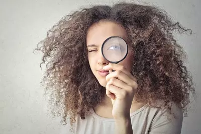 Woman holding a magnifying glass to her eye