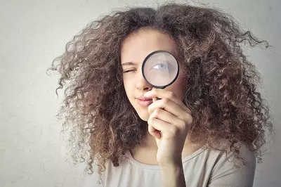 Woman holding magifying glass to her eye