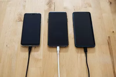 3 phones on a desk with USB C cables plugged into them