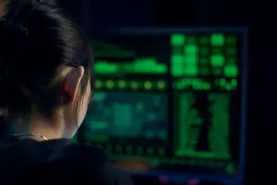 Woman looking at glowing green monitors