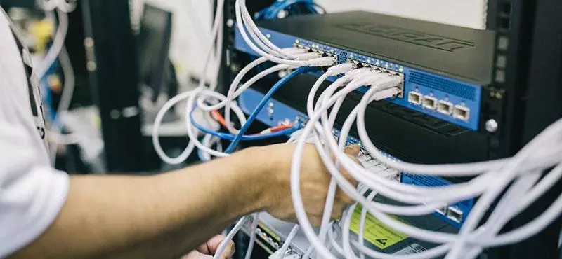 Man plugging wires into network switch